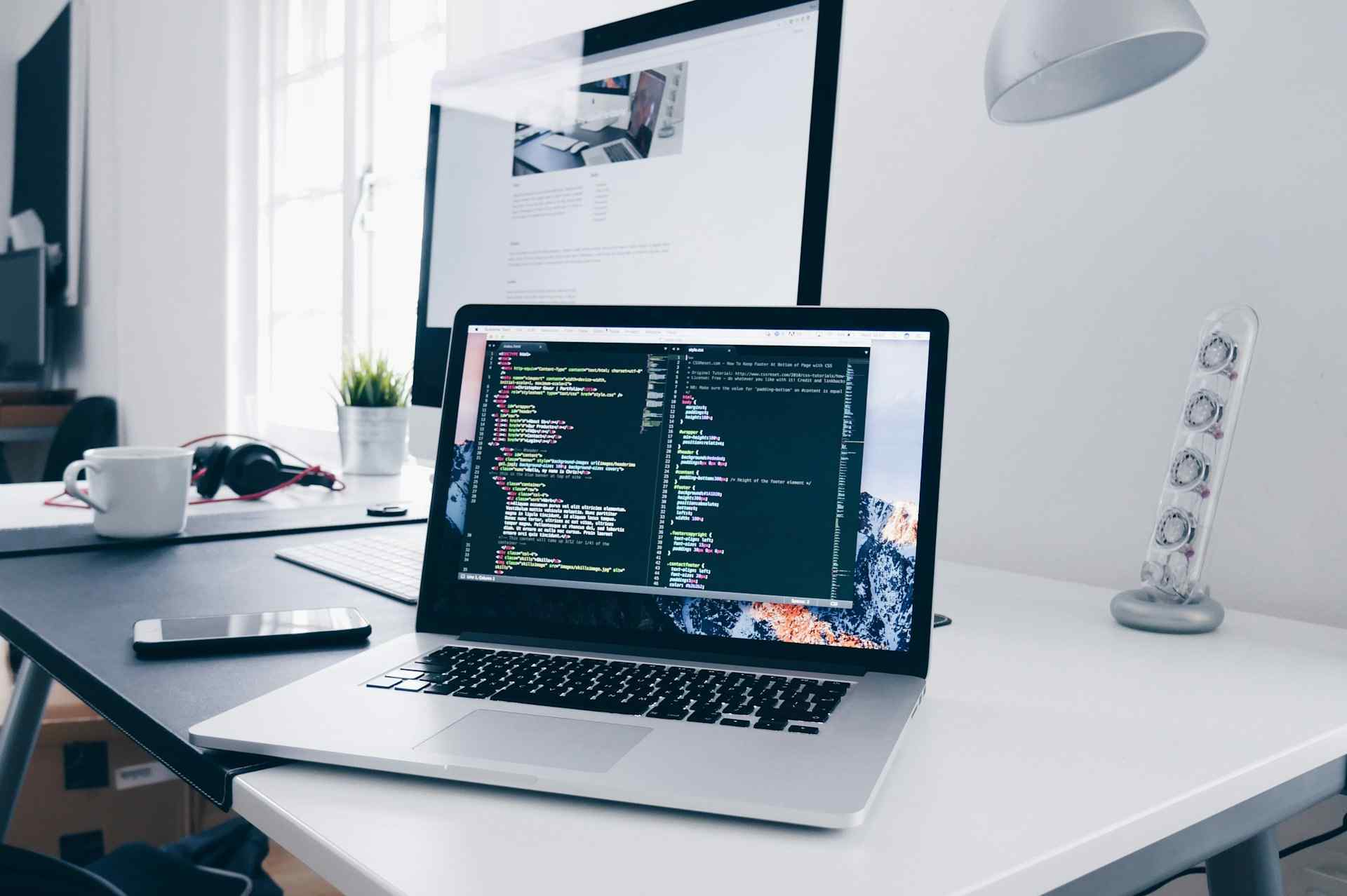 Hero image of a laptop on a desk with code on the screen